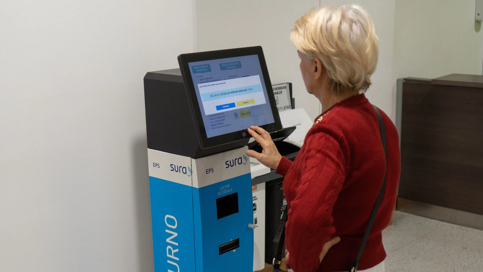 Femme âgée demandant son ticket sur une borne tactile en libre-service avec lecteur de documents intégré